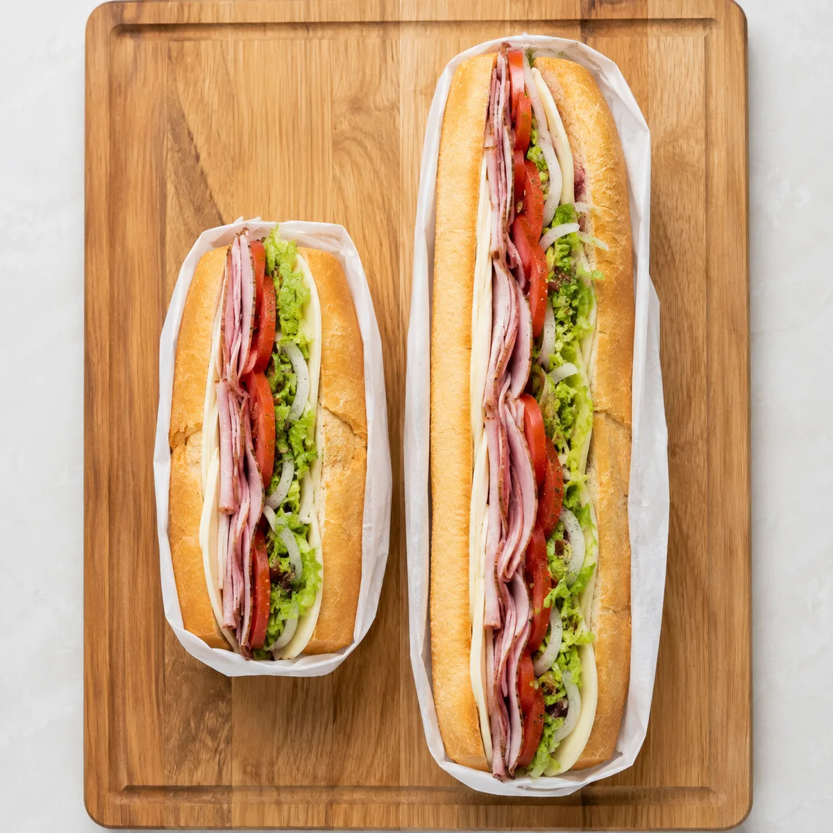 Jersey Mike's regular sub next to a giant sub on a wooden board, showing the size difference